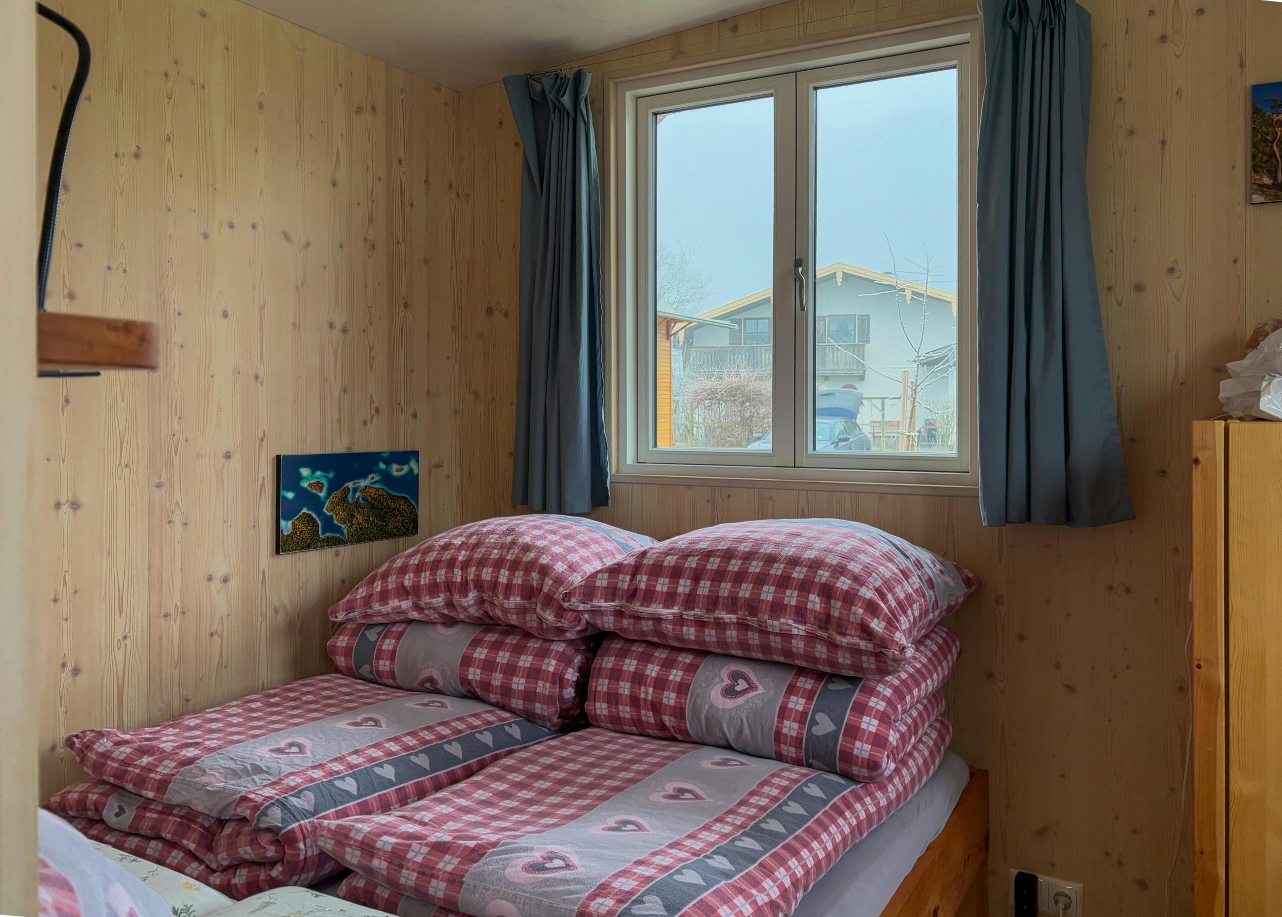 Cozy pine-paneled bedroom with checked and heart-patterned bedding