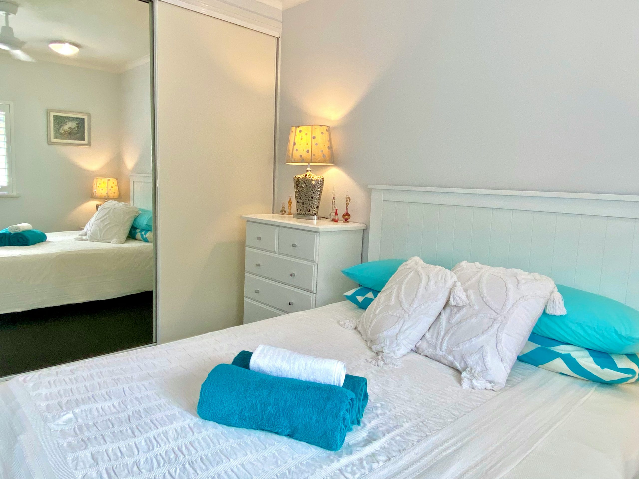 Crisp White Bedroom with Teal Accents and Patterned Lamp